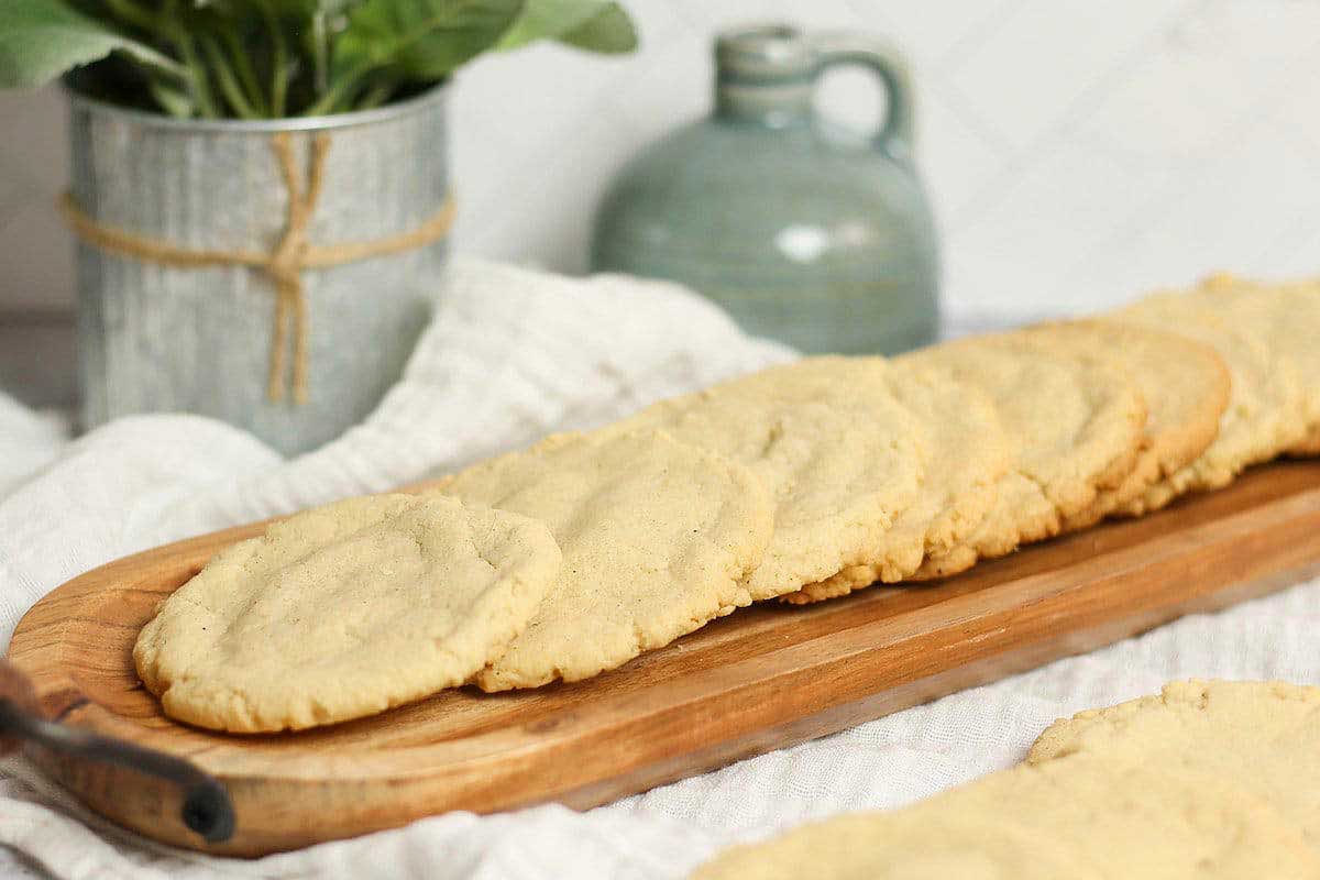 Sugar cookies on a wooden cutting board.