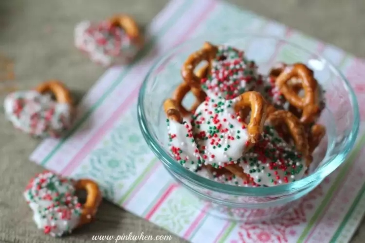 Christmas pretzels in a glass bowl with sprinkles, perfect for festive candy recipes.