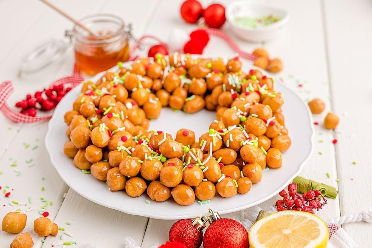 A plate with a wreath of nuts and lemons on it, perfect for Christmas recipes.