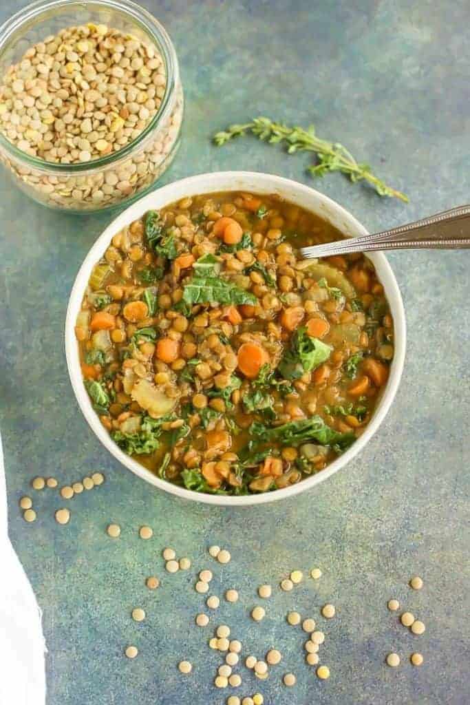 A bowl of lentil soup with a spoon next to it.