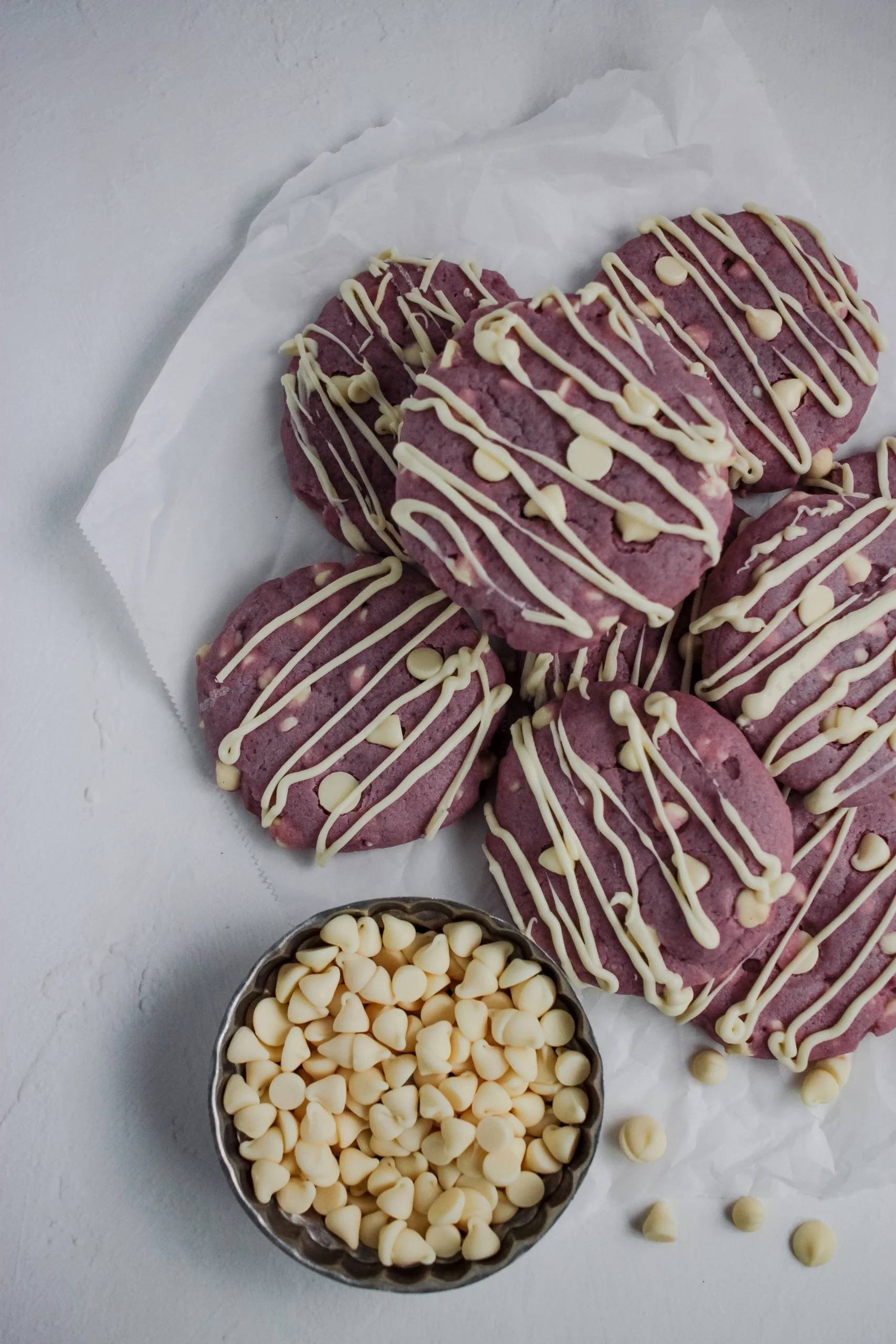 A plate of cookies with white icing and chocolate chips, made from unique cookie recipes.