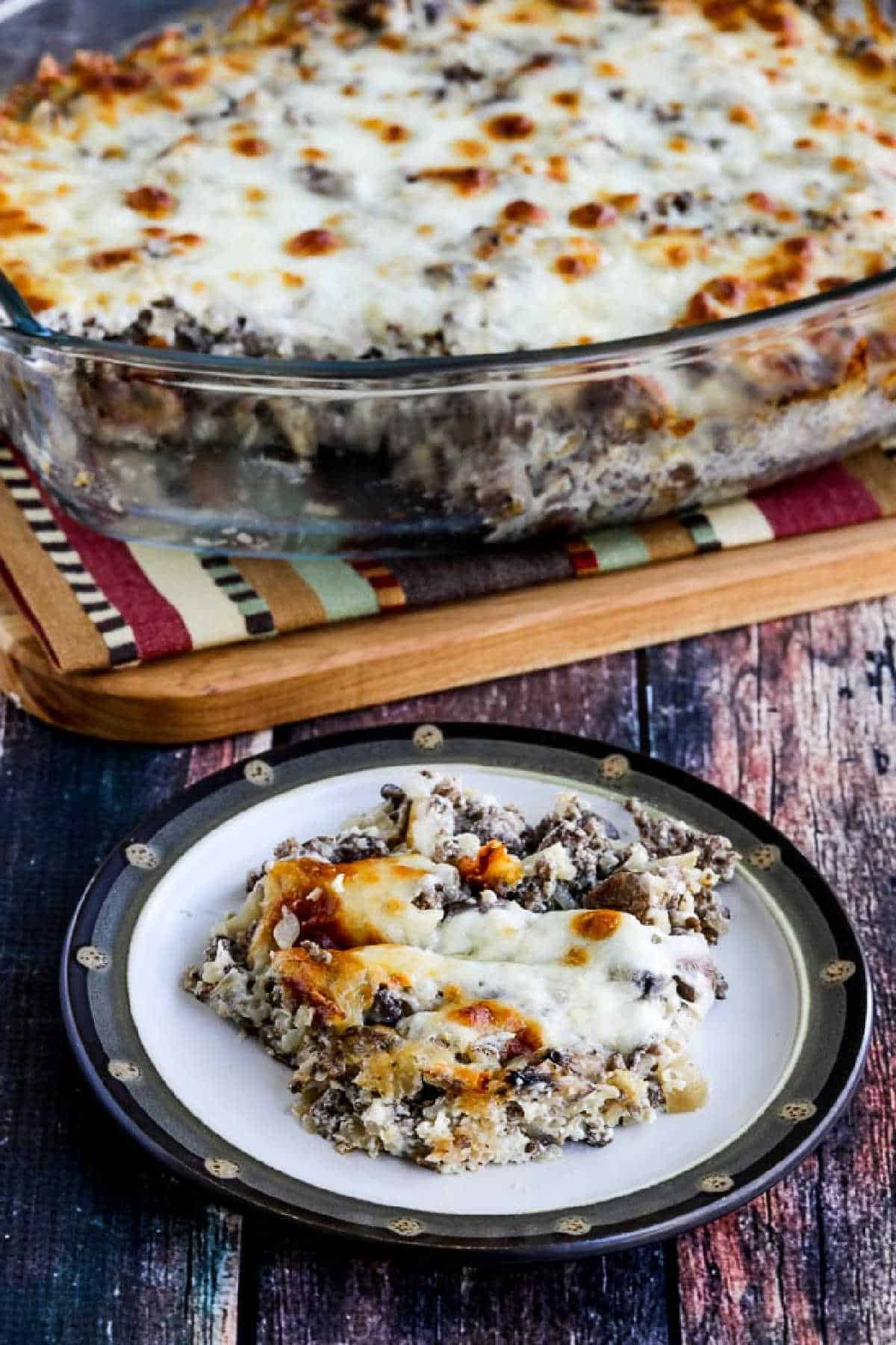 Ground Beef Stroganoff Casserole with one serving on plate and casserole dish in background.
