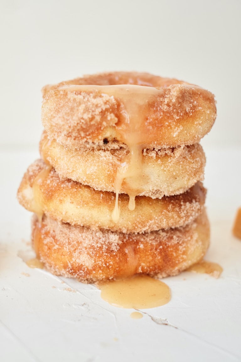 A stack of unique donuts with caramel sauce on top.