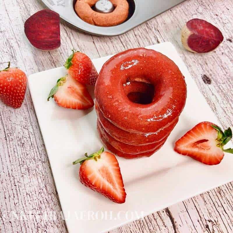 A plate with unique donut flavors and strawberries on it.