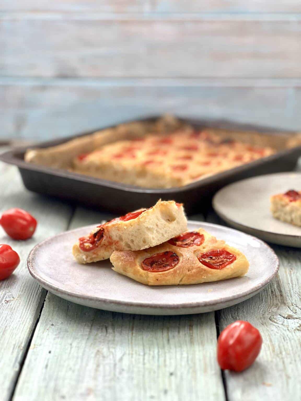 Cherry Tomato Focaccia Plated with the tray of focaccia in the background.
