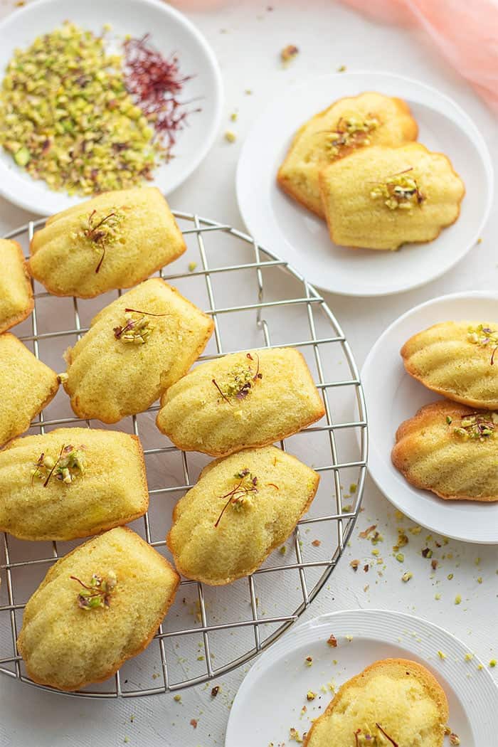 Unique pistachio macaroons on a cooling rack with pistachios.