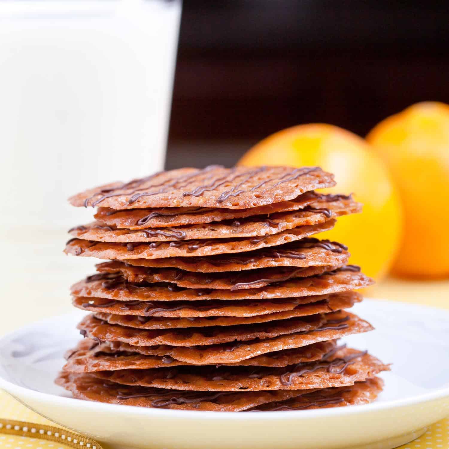 A stack of unique cookies on a plate next to a glass of milk.