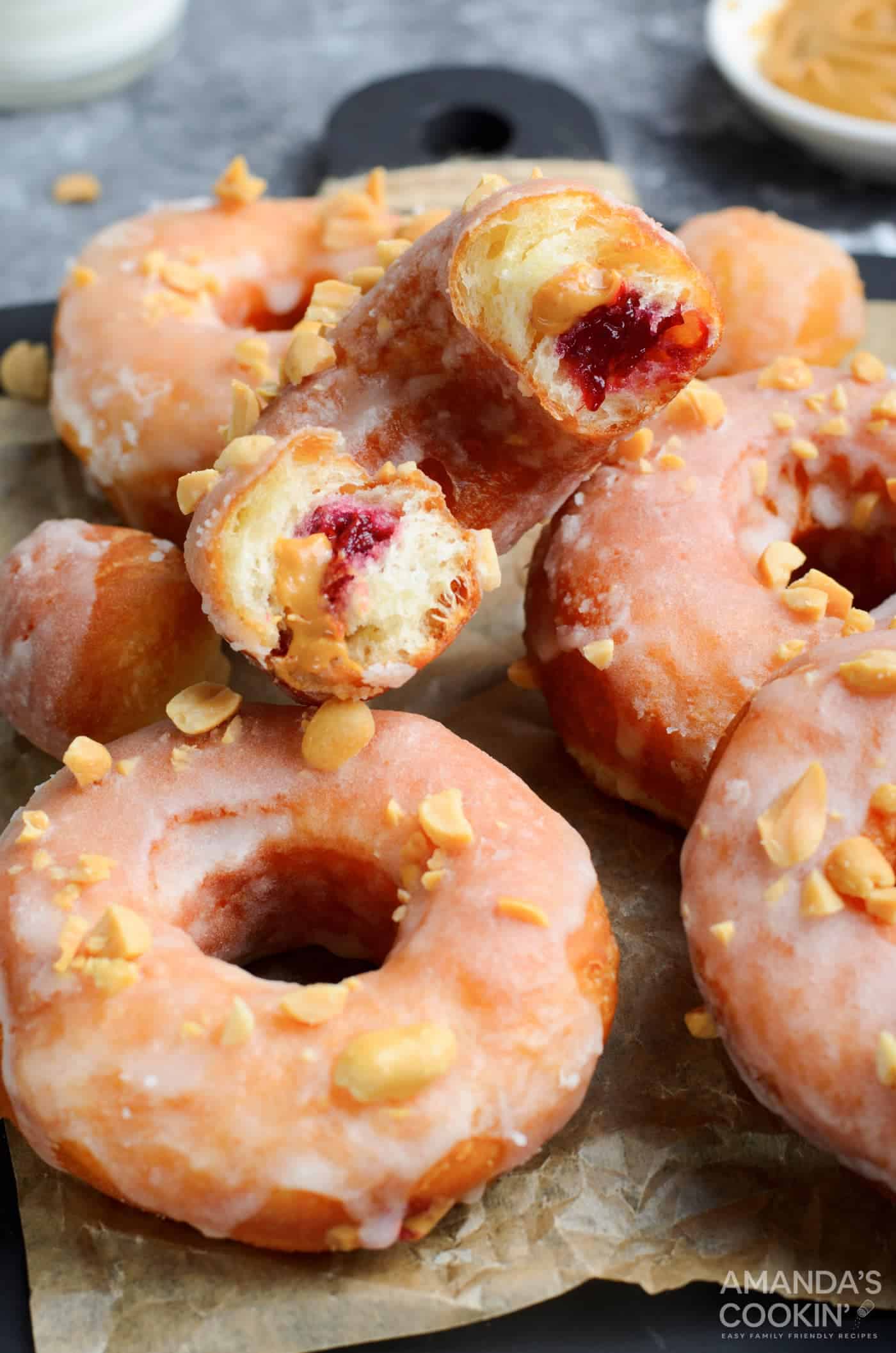         Description: A tray of donuts with unique flavors, including one with a bite taken out of them.