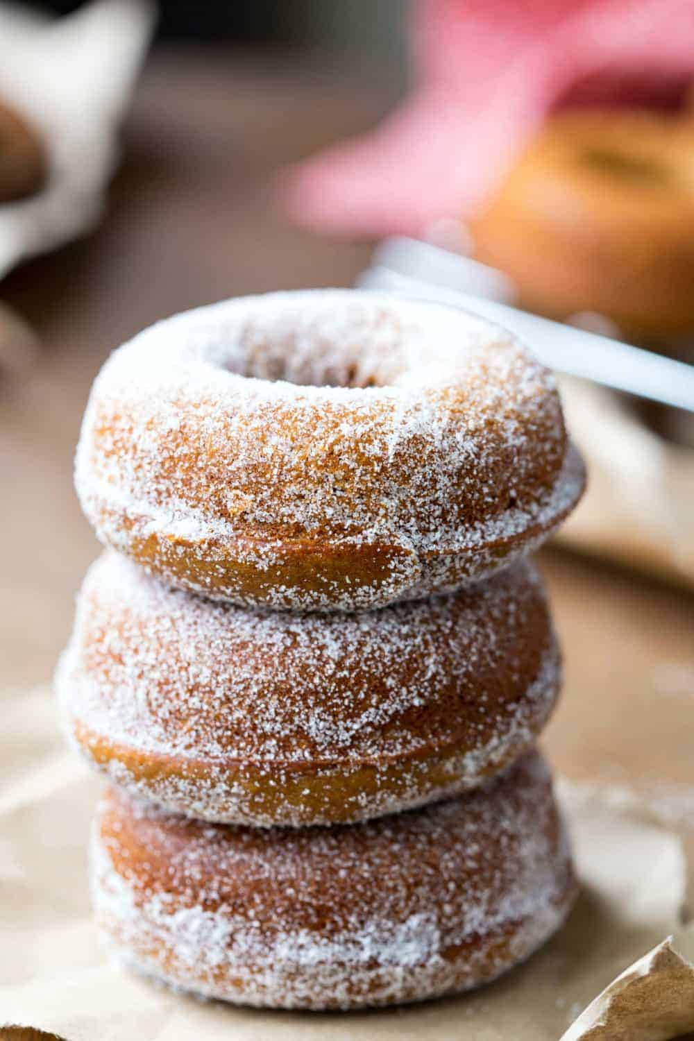 A unique stack of donuts with powdered sugar on top, featuring innovative donut flavors.