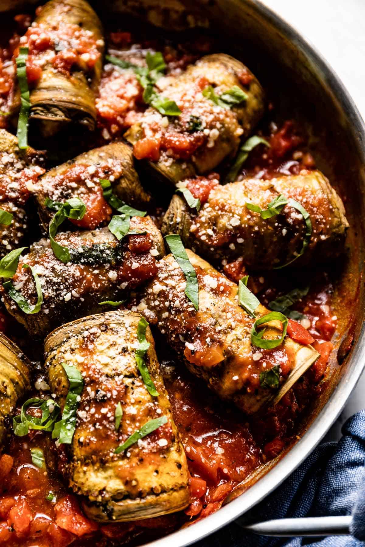 aubergine ricotta rolls in a skillet in tomato sauce.
