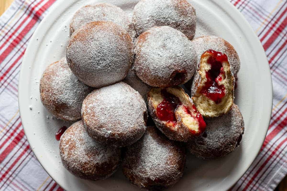 A plate of donuts with unique donut flavors, jam and powdered sugar.