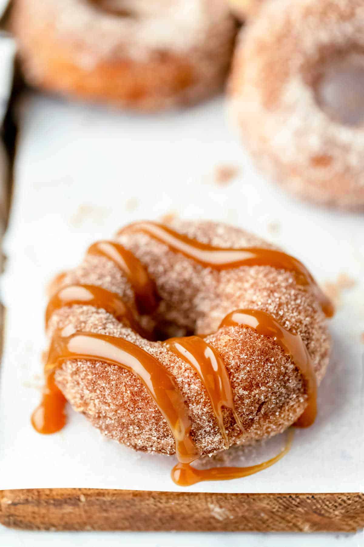 Unique caramel glazed doughnuts on a cutting board.