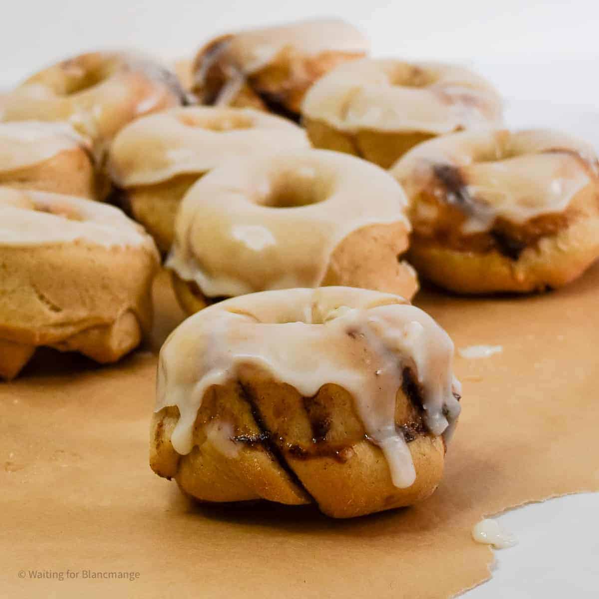 Cinnamon donuts with unique icing on a piece of paper.