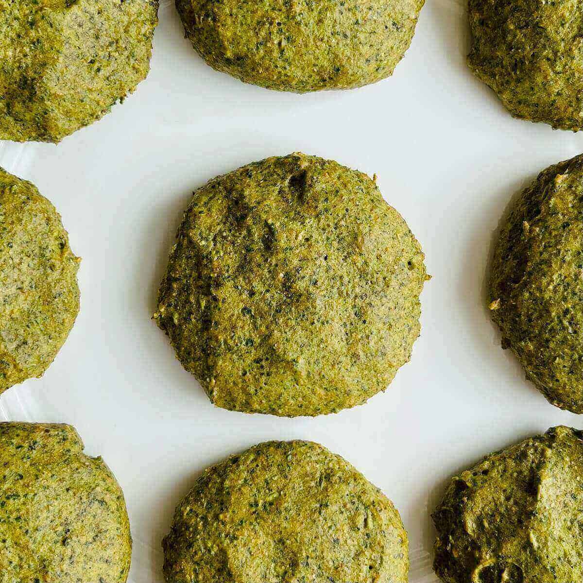 A plate of unique green cookies on a white plate.