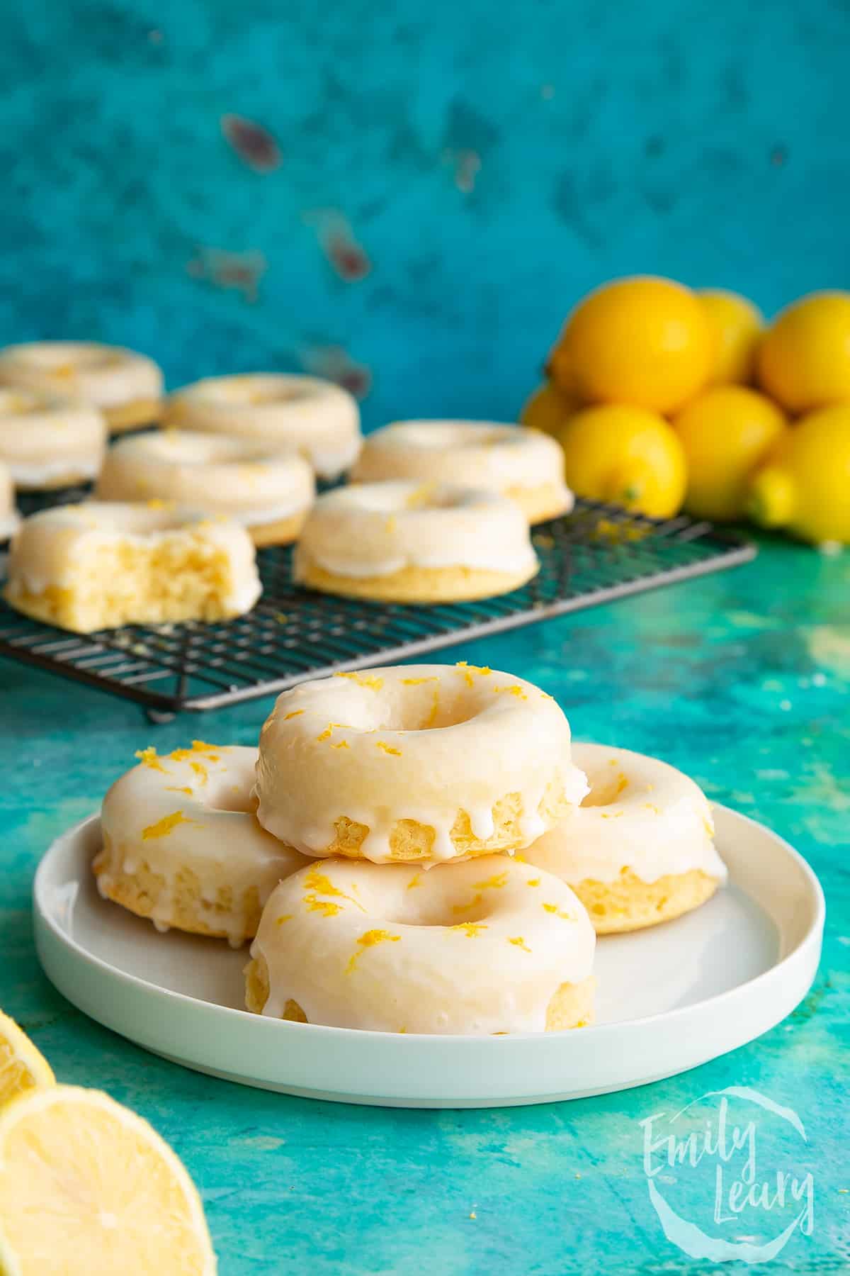 Unique lemon donuts on a plate with lemons in the background.