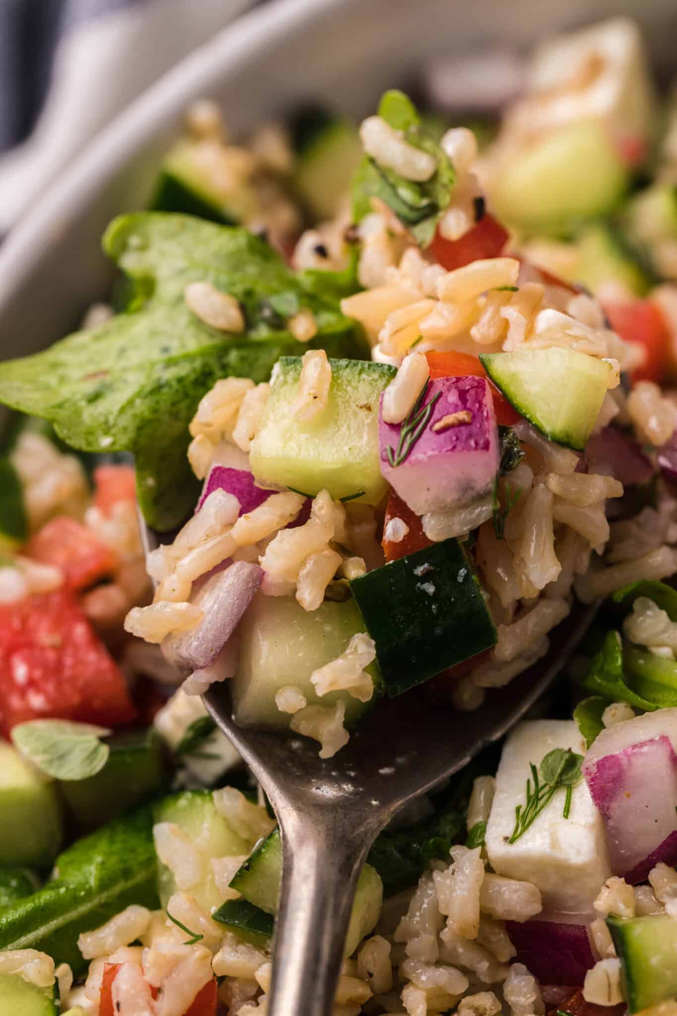 Scooping out a Mediterranean rice salad from a bowl. 
