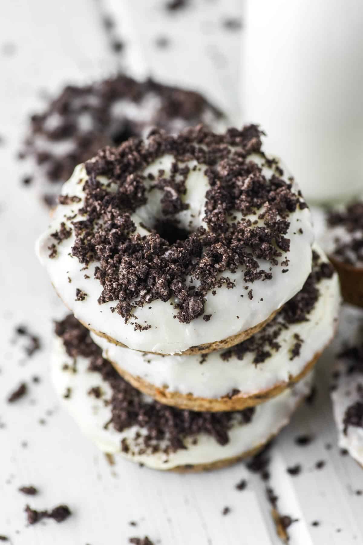 A stack of unique oreo donuts with a glass of milk.