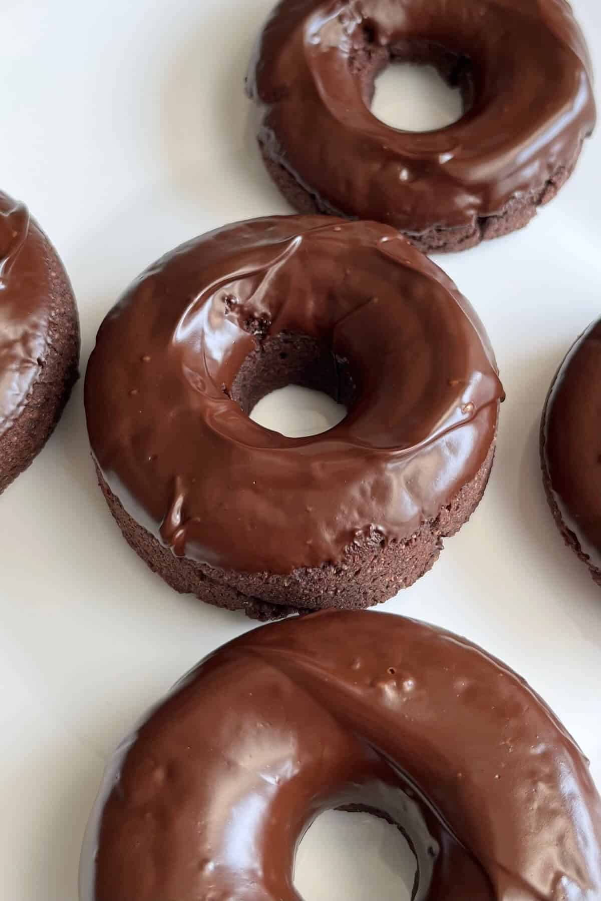 Chocolate glazed donuts with unique flavors on a white plate.