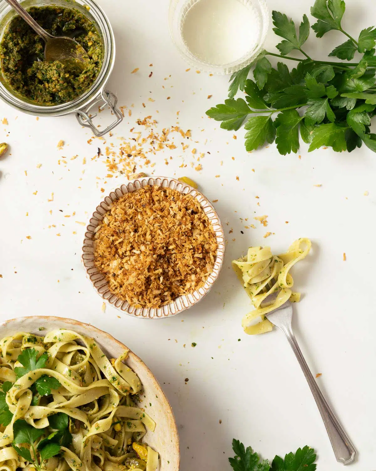 A fork with pasta on it, and a bowl of pangritata. 
