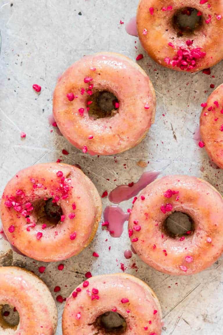 Unique donuts with pink sprinkles on a baking sheet.