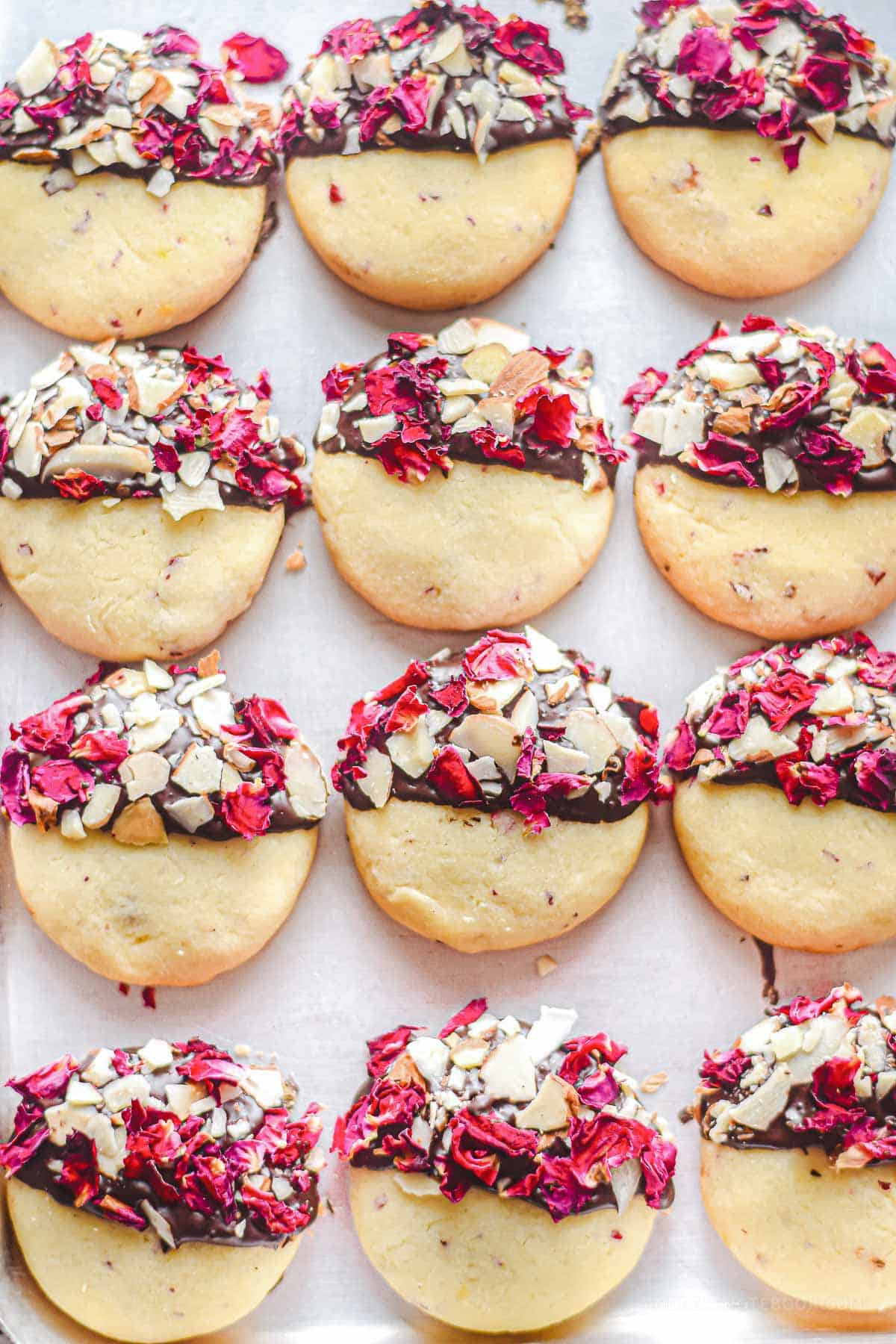 A tray of unique cookies covered in roses and chocolate.