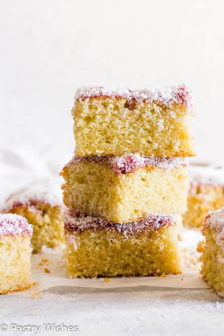 three pieces of coconut and jam cake stacked on top of each other.
