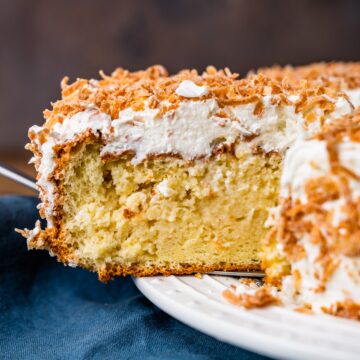 A coconut cake with white frosting and sprinkles on a plate.